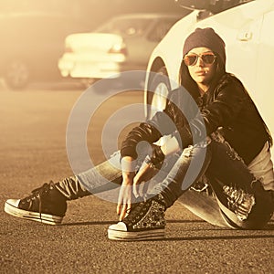 Young fashion hipster woman sitting next to her car