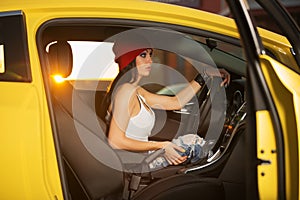 Young fashion hipster woman in white tank top sitting in car