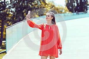 Young fashion influencer woman taking a selfie outdoor with her smartphone