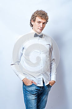 Young fashion male model wearing bow tie on gray