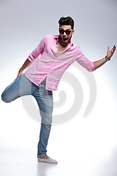 Young fashion man balancing with one leg in his hand