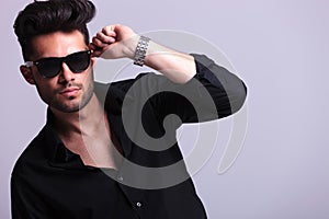 Young fashion man with hand on sunglasses