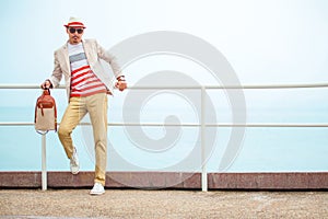 Young fashion man in hat holding bag near sea
