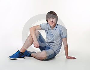 Young fashion man posing in jeans shorts and blue sneakers shoes