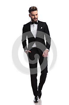 Young fashion man in tuxedo walks and looks down