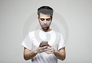 Young fashion man wearing casual typing sms on grey background
