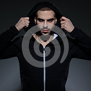 Young fashion man wearing gym suit and pulling hoodie