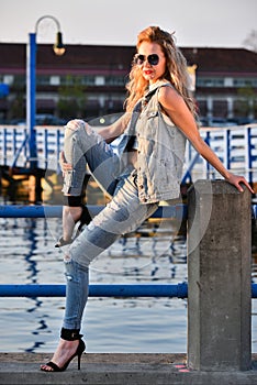 Young fashion model posing pretty on the pier.