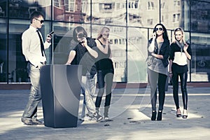 Young fashion people talking on cell phones in city street