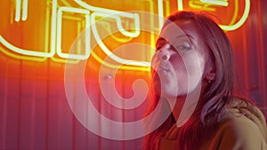 Young fashion teen girl blowing bubble gum illuminated with street neon red japanese sign, beautiful millennial woman in