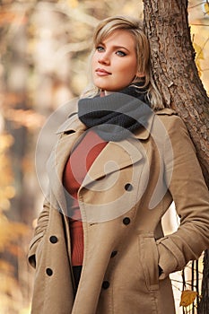 Young fashion woman in beige coat in autumn park