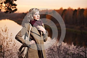 Young fashion woman in beige coat with handbag walking outdoor