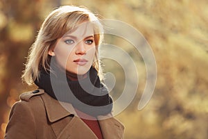 Young fashion woman in beige coat walking in autumn park