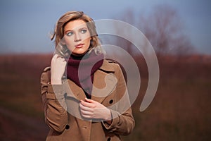 Young fashion woman in beige coat walking outdoor