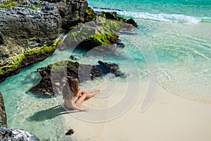 Young fashion woman in bikini looking on sea at tropical beach.