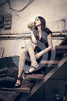 Young fashion woman in black dress in old artist studio sit on s