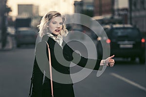 Young fashion woman hailing a taxi cab in city street