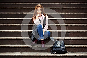 Young fashion woman with handbag sitting on steps