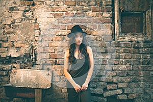 Young fashion woman with hat stand in front old abandoned house