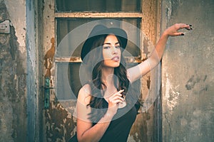 Young fashion woman with hat stand in front old abandoned house