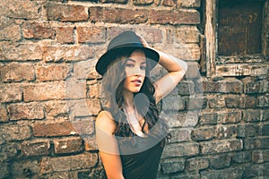 Young fashion woman with hat stand in front old abandoned house