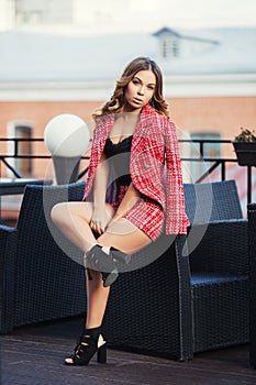 Young fashion woman in red tweed jacket and shorts suit at sidewalk cafe