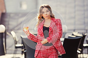 Young fashion woman in red tweed jacket and shorts suit at sidewalk cafe