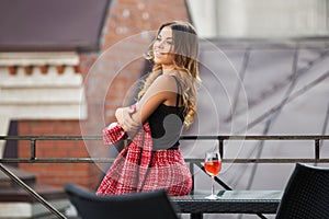 Young fashion woman in red tweed jacket and skirt suit at sidewalk cafe