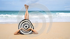 Young fashion woman relax on the beach. Happy island lifestyle. White sand, blue cloudy sky and crystal sea of tropical beach.