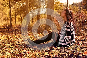 Young fashion woman sitting in autumn leaves