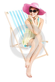 Young fashion woman smiling and sitting on a beach chair