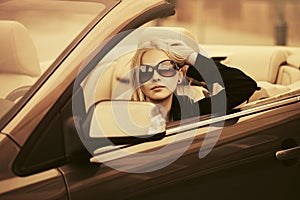 Young fashion woman in sunglasses driving convertible car
