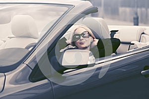 Young fashion woman in sunglasses driving convertible car