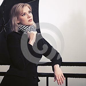Young fashion woman with umbrella leaning on railing outdoors