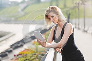 Young fashion woman using digital tablet computer on city street