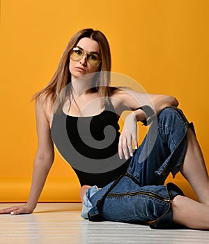 Young fashion woman wearing unbuttoned jeans legs and black sexy swimsuit on yellow