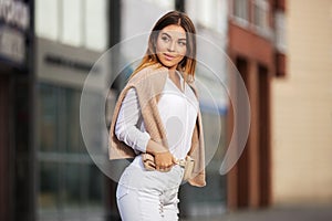 Young fashion woman in white shirt and ripped jeans walking in city street