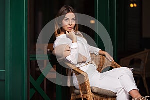 Young fashion woman in white shirt sitting on wicker chair