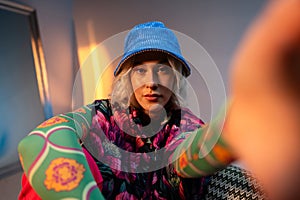 A young fashionable blonde sits on a chair and looks deeply into the camera in the studio