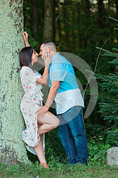 Young fashionable couple in love and kissing outside by tree