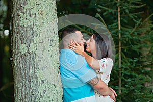 Young fashionable couple in love and kissing outside by tree