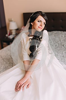 Mladý módní vzrušený nevěsta na postel v svatba šaty a snění z její nový ženatý život 