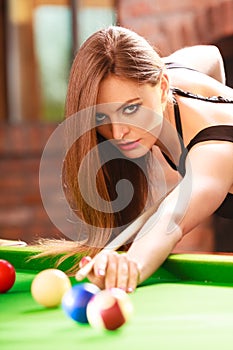 Young fashionable girl playing billiard.