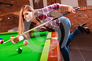 Young fashionable girl playing billiard.