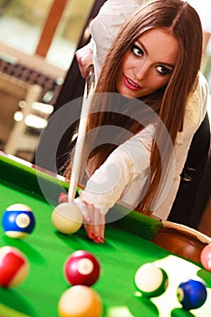 Young fashionable girl playing billiard.