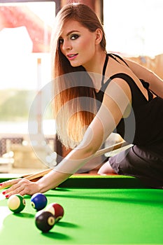 Young fashionable girl playing billiard.