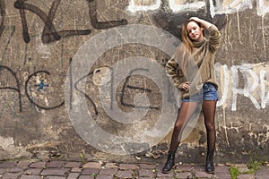 Young fashionable girl posing near the old wall.