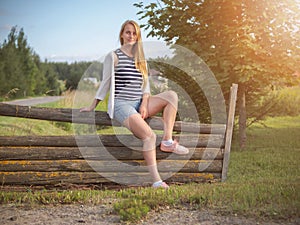 Young fashionable happy blonde woman posing in rural landscape.