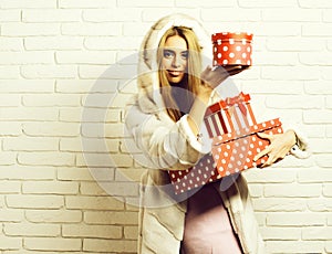 Young fashionable pretty woman or girl with long beautiful blonde hair in waist coat of white fur with hood and
