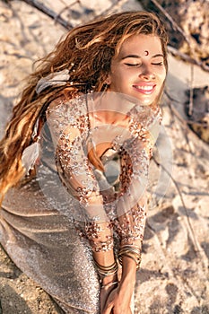 Young fashionable woman sitting on the stone beach portrait